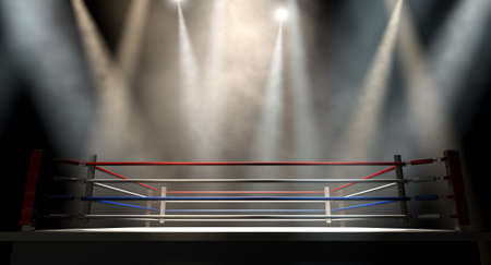 A regular boxing ring surrounded by ropes spotlit by various lights on an isolated dark backgroundの写真素材