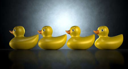 A row of organised and ready yellow rubber bath duck toys on an isolated dark backgroundの写真素材