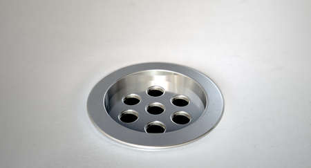 A closeup of a chrome plug hole set in a porcelain basinの写真素材