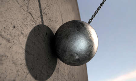 A regular metal wrecking ball attached to a chain hitting a concrete surface