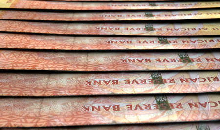 A macro close-up view showing the detail of south african rand banknotes laid out and overlapping in...