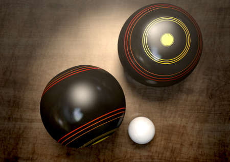 Two wooden lawn bowling balls surrounding a white jack on a wooden isolated dark studio backgroundの写真素材