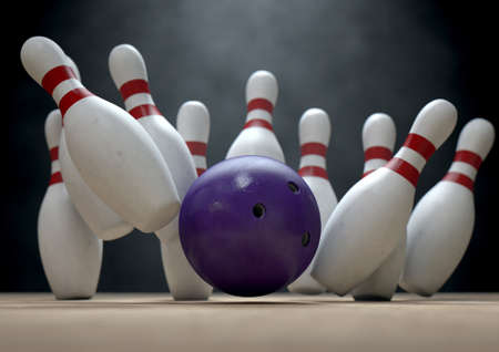 An arrangement of white and red used vintage bowling pins being struck by a bowling ball on a wooden bowling alley surface on a dark backgroundの写真素材
