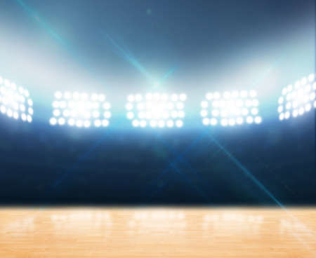 An indoor gynasium with an unmarked wooden floor under illuminated floodlightsの写真素材