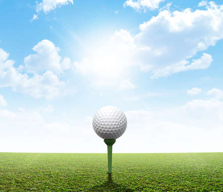 A perfect flat green lawn against a blue sky with white cloudsの写真素材