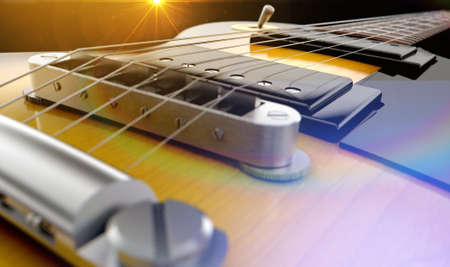 An abstract closeup of the body section of an electric guitar under dramtic lighting conditons