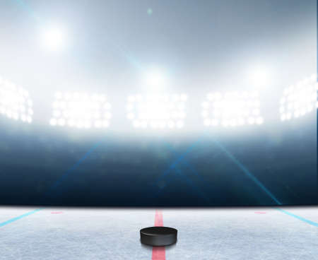 A generic ice hockey ice rink stadium with a frozen surface and a hockey puck under illuminated floodlightsの写真素材