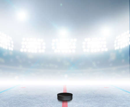A generic ice hockey ice rink stadium with a frozen surface and a hockey puck under illuminated floodlightsの写真素材