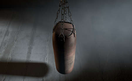 A 3D render of an old worn vintage leather punching bag in a room dark room lit by an ethereal spotlightの写真素材