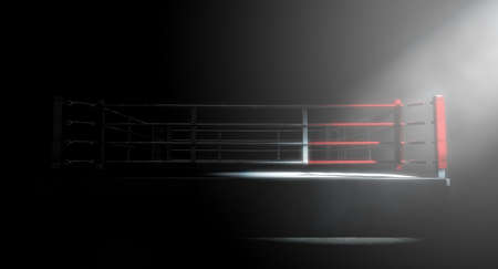 A 3D render of a modern boxing ring with a blue and red area spotlit dramatically on one corner on an isolated dark backgroundの写真素材