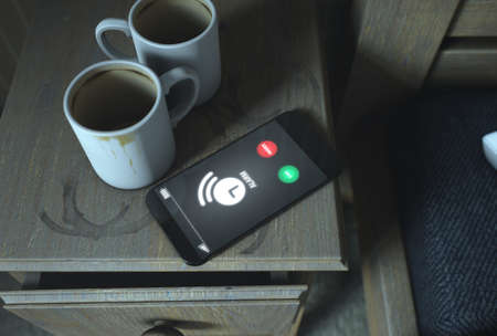 A real life concept scene showing a bed side table with dirty coffee mugs and a generic illuminated...