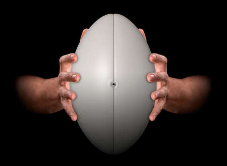A pair of male hands clamping a rugby ball on an isolated dark background - 3D renderの写真素材