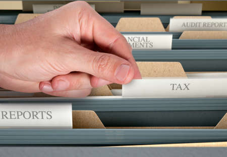 A male hand searching through documents in a filing cabinet drawerの写真素材