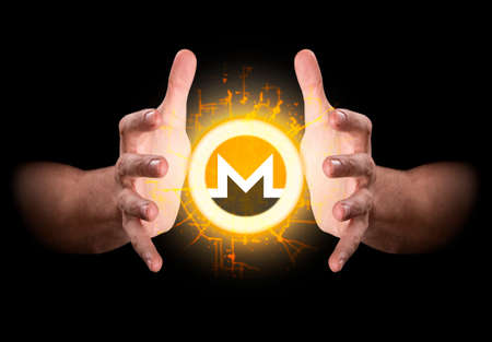 A pair of male hands reaching through the dark grasping at a monero coin hologramの写真素材