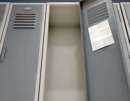A row of metal school lockers with one open door and a blank page note taped to the inside - 3D renderの写真素材
