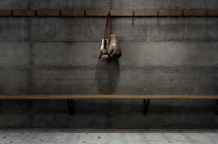 Spotlit old vintage boxing gloves hanging on a hanger above an empty wooden bench in a locker change room - 3D renderの写真素材