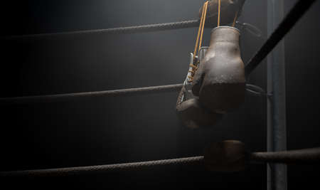 A closeup of the corner of an old vintage boxing ring surrounded by ropes spotlit by a spotlight on an isolated dark background - 3D renderの写真素材