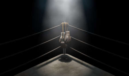 A closeup of the corner of an old vintage boxing ring surrounded by ropes spotlit by a spotlight on an isolated dark background - 3D renderの写真素材