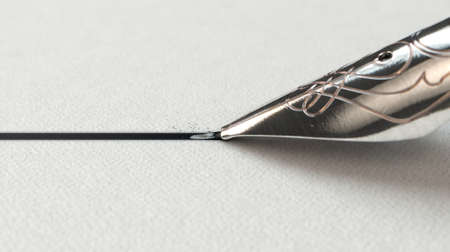 A closeup view of an ornate metal nib of an old fountain pen drawing a straight ink line on a...