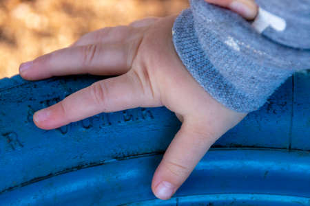 A Little girls hand resting on a reused blue rubber tyreの写真素材