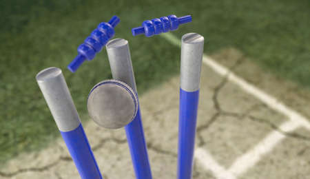 A white leather cricket ball hitting blue cricket wickets on a cracked grass pitch background - 3D...
