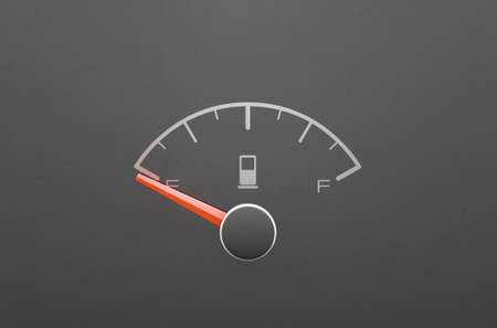 A closeup of a petrol gas gage showing the needle at empty on a dark reflective background with copy...