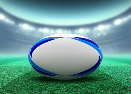 A reguar white rugby ball with blue design elements resting on a stadium grass pitch at night under illuminated floodlights - 3D renderの写真素材