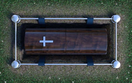 A modern wooden coffin at a funeral being lowered into a grave with a lowering mechanism a dirt and...