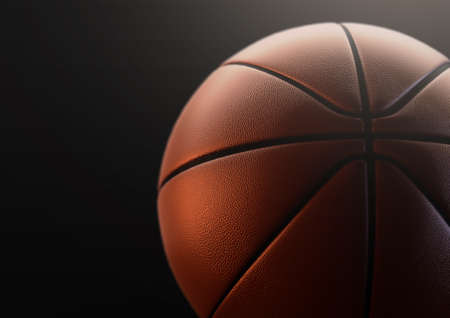 A regulation orange and black rubber basketball in dramatic lighting on an isolated black studio background - 3D renderの写真素材
