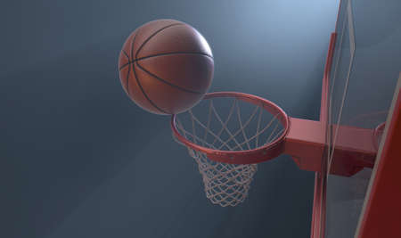 An action shot of a regular basketball teetering on the rim of a red basketball hoop dramatically...