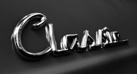 A closeup view of the word classic written as a chrome emblem in a retro font set on a car painted in reflective red paint - 3D renderの写真素材