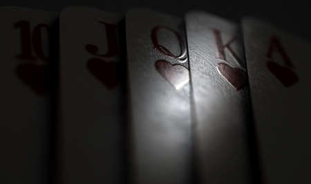 A close up of fanned out royal flush suit of five casino playing cards on a dimly lit background - 3D renderの写真素材
