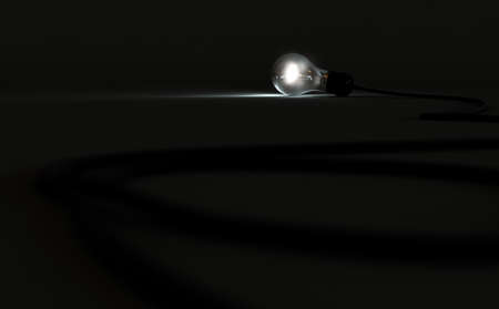 A concept of a draped light cord with a standard light bulb brightly illuminated on a dark...