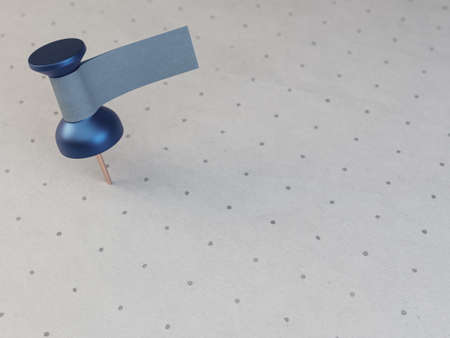 A blue thumbtack with a blank tape tag attached to it on a textured and printed paper surface -3D renderの写真素材