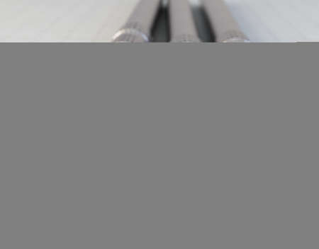 A set of stainless steel dentists tools resting on a graph paper surface - 3D render
