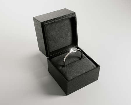 An open cube shaped black ring box with a silver engagement ring and large cut diamond on an...