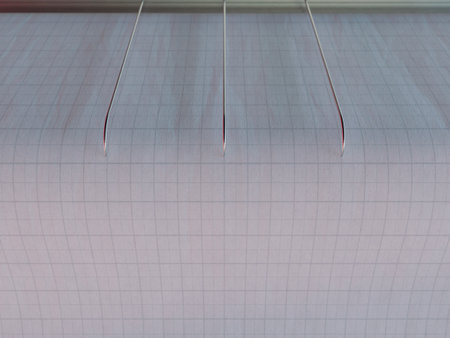 A closeup of seismograph machine needles on graph paper depicting seismic and eartquake activity -...
