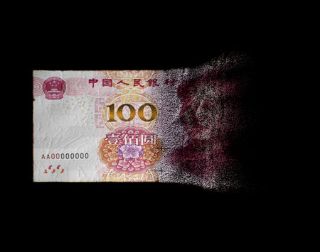 A concept image showing a half dissolved flat paper chinese yuan bank note on a dark studio...