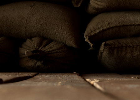 A dim indoor stage of a worn wooden floor and burlap hessian sacks on a dark background - 3D renderの写真素材