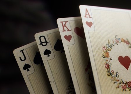 Closeup image of four vintage playing cards featuring jack, queen, king, and ace on a dark...
