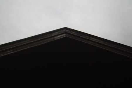 black roof of an old house with a cloudy sky in the background