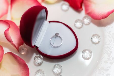 Wedding ring in rose petals against the background of candlesの写真素材