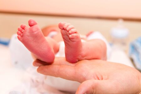 Newborn's legs are small in the hands of parents.