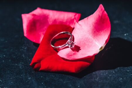Wedding ring on rose petals. Dark backgroundの写真素材