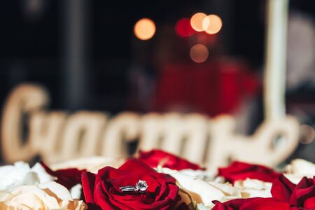 Wedding ring on rose petals. The inscription in Russian happiness