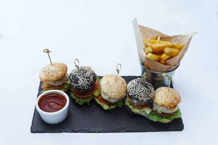 Hamburgers and French fries on a black plateの写真素材