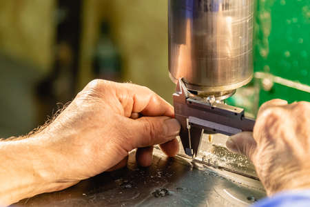 Factory man worker measuring steel detail with digital Vernier Caliper at workshop