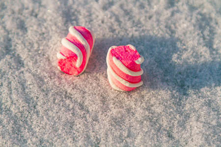 marshmallow lies on a white snow-covered background. Winter Christmas background