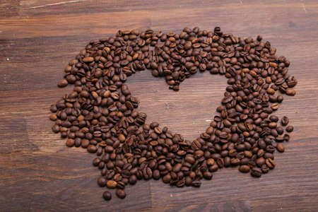 Heart shape made from coffee beans on wooden surfaceの写真素材