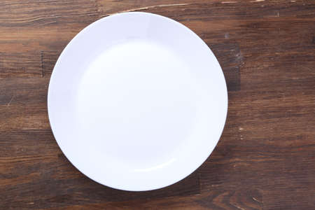 empty plate waiting for food, sitting on wooden table, top view, copy space. Hunger and lunch time concept.の写真素材